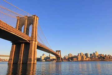 Naklejka premium Brooklyn Bridge over East River with view of New York City Lower Manhattan, waterfront at twilight, USA