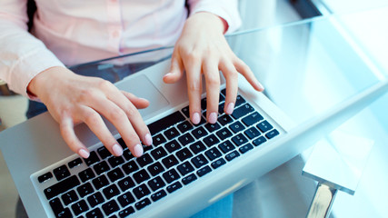 Fototapeta na wymiar Close up of female hands using laptop computer, indoors.