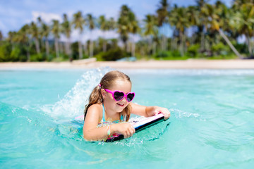 Kids surf on tropical beach. Vacation with child.