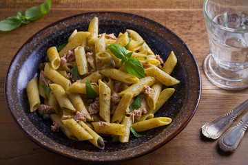 Tuna, basil and caper penne with pesto sauce in bowl on wooden background. Pasta with tuna fish. overhead, horizontal