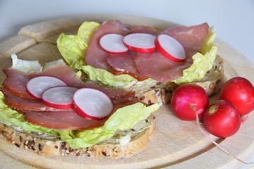 sandwich with smoked ham on a lettuce leaf with slices of radish