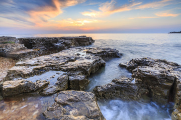 Enjoying the colorful sunset on a beach with rocks on the Adriatic Sea coast Istria Croatia