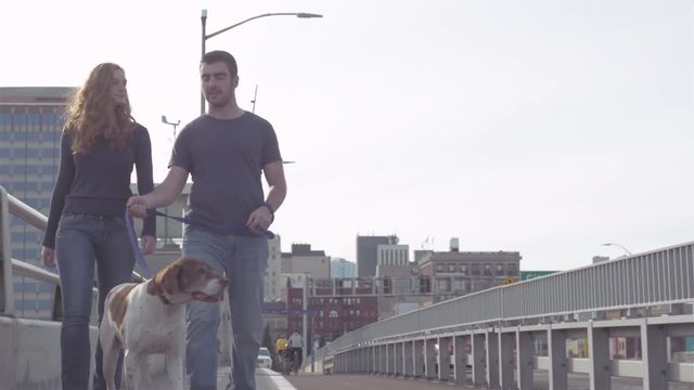 Young loving couple walking their adorable dog on a bridge