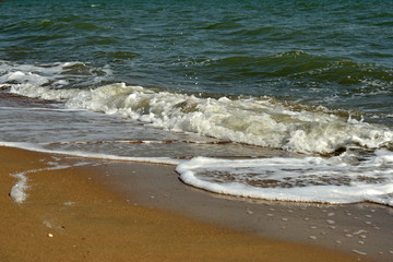 Coast of the sea with stormy waves and sand. The concept of summer holidays during the holidays.