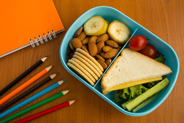 School lunch in the box, pencils and notebook on the table.Top view.