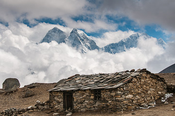 stone building with mountains and clouds on trail to everest nepal