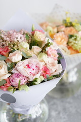 two bouquet of beautiful flowers on gray table. Floristry concept. Spring colors. the work of the florist at a flower shop. Vertical photo