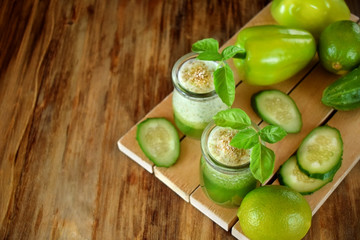 Green smoothie in glass jars sprinkled with brans decorated with basil on wooden background. Top view