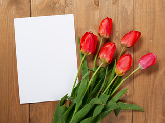 tulips are on wooden boards, blank paper sheet with place for text - holiday and greeting concept