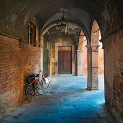 Fototapeta na wymiar Ancient arcade & bikes in Lucca, Tuscany, square