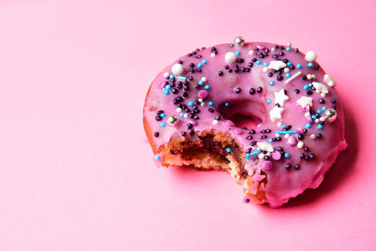 Bitten pink donut with a festive powder.