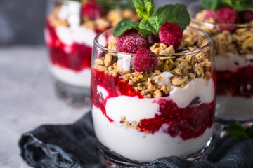 Yogurt parfafait with granola and raspberries in glass.