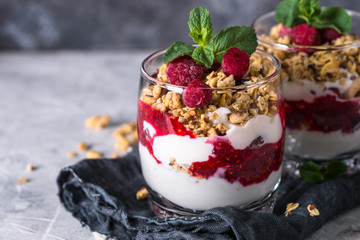 Yogurt parfafait with granola and raspberries in glass. - obrazy, fototapety, plakaty