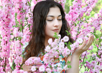Fototapeta premium portrait of young girl on pink flowers background, face close up