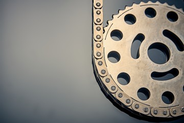 Roller chain with sprocket on dark background. It is used on cars, motorcycles, bicycles and in mechanical engineering.