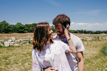 Lovely couple having fun outdoors playing with colorful holi powder. Lifestyle portrait