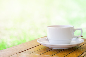 Cup of coffee on wooden table with green light bokeh background