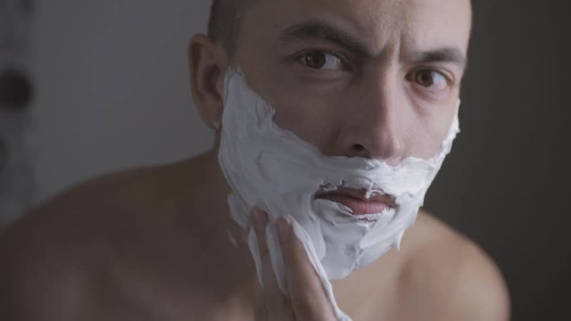 Adult man shaving with foam and manual razer