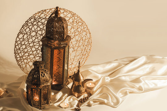 Unique mental lanterns and Arabic coffee pot on satin linen used as decoration symbols in Ramadan month.