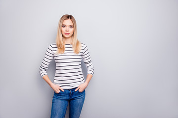 Portrait with copy space, empty place for advertisement of pretty, charming, nice, cute woman holding two hands in pockets of jeans looking at camera isolated on grey background