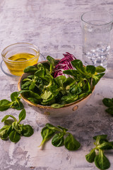 Vegetable mixed salad and olive oil, on concrete white background, flat lay view, vertical.