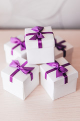 Wedding bonbonniere, white boxes with purple bows. Gifts to guests. Wedding decor, style, selective focus.