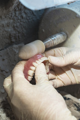 Dental technician working on dental prosthetic for to polish up