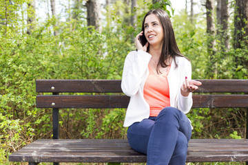 Obraz premium Attractive smiling young woman with smartphone in the park