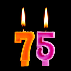 Burning birthday candles in the form of 75 seventy five figures for cake isolated on black background. The concept of celebrating a birthday, anniversary, important date, holiday