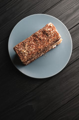 Traditional Italian dessert tiramisu on a gray plate on a black wooden background