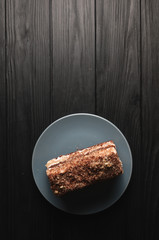 Traditional Italian dessert tiramisu on a gray plate on a black wooden background