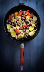 pan with fried chicken hearts and vegetables