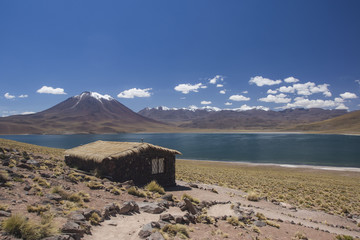 miscanti volcano with snow and its lagoon at andes mountain range with a house