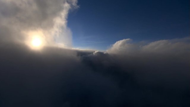 Flying through cloud plume with haloed sun 