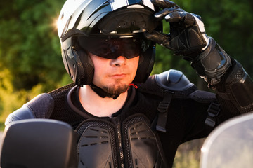 rider on a motorcycle taking off his helmet - summer road trip on a motorbike