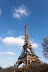 Fototapeta premium Tour Eiffel against blue sky and white clouds. The metal structure landmark has become the symbol of Paris and France. Feb 2018.