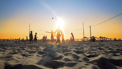 Bunch of people play beach volleyball at Beach / people enjoying beach volley at sunset