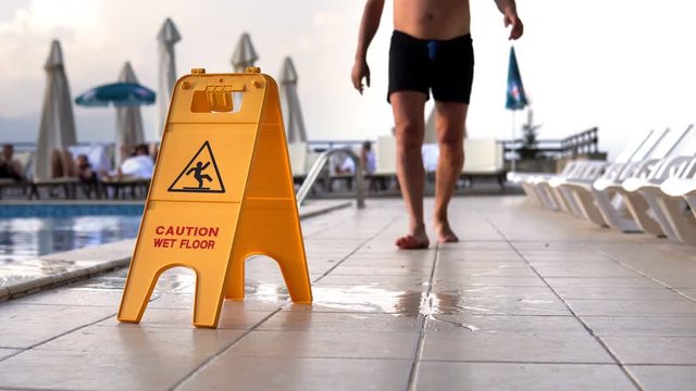 Man walks and fall because of slippery surfaces by yellow wet floor surface warning sign