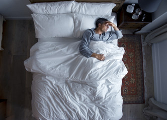 Man on bed with a headache - obrazy, fototapety, plakaty