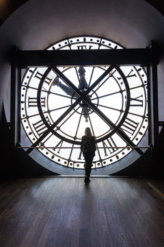 Girl silhouette standing in front of vintage clock tower with roman numbers. Paris Orsay Museum.