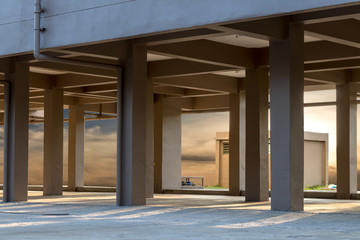 Sunlight shines through the concrete pillars under the building.