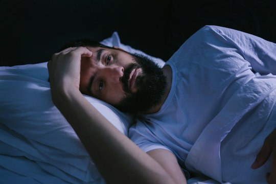 Young man in bed with eyes opened suffering insomnia and sleep disorder