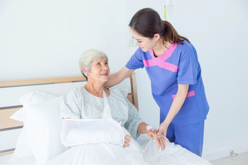 Senior asian female patient smiling with nurse who come to visit her at bed