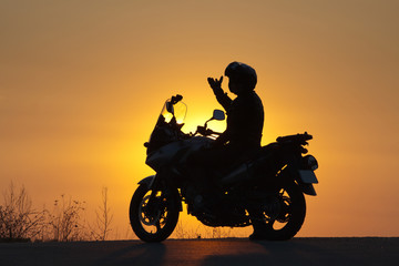 Obraz na płótnie Canvas silhouette of rider on a motorbike admiring sunset - space for your text
