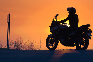 Plakat silhouette of rider on a motorbike admiring sunset - space for your text