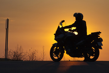 Fototapeta na wymiar silhouette of rider on a motorbike admiring sunset - space for your text