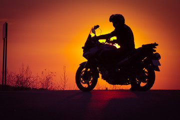 silhouette of rider on a motorbike admiring sunset - space for your text