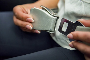 Fashion model female passenger fastening seat belt while sitting on the airplane for safe flight