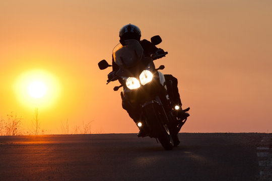 silhouette of rider on a motorbike driving at sunset - space for your text