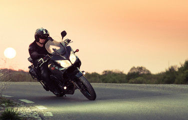 Naklejka premium sylwetka jeźdźca na motocyklu jazdy o zachodzie słońca - miejsce na tekst